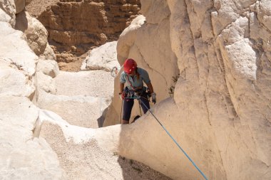 Kudüs, İsrail, 16 Nisan 2022: Deneyimli bir atlet, İsrail 'in Kudüs yakınlarındaki Tamarim deresi yakınlarındaki Musevi Çölü' nün dağlarında kırılma ekipmanlarıyla birlikte iniyor.