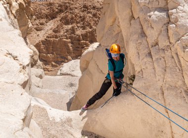 Kudüs, İsrail, 16 Nisan 2022: Deneyimli bir atlet, İsrail 'in Kudüs yakınlarındaki Tamarim deresi yakınlarındaki Musevi Çölü' nün dağlarında kırılma ekipmanlarıyla birlikte iniyor.