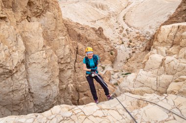Kudüs, İsrail, 16 Nisan 2022: Tecrübeli bir atlet, İsrail 'in Kudüs yakınlarındaki Tamarim deresi yakınlarındaki Musevi Çölü' nün dağlarında kırılacak aletlerle baş aşağı iniyor.