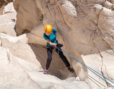 Kudüs, İsrail, 16 Nisan 2022: Deneyimli bir atlet, İsrail 'in Kudüs yakınlarındaki Tamarim deresi yakınlarındaki Musevi Çölü' nün dağlarında kırılma ekipmanlarıyla birlikte iniyor.