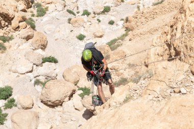 Kudüs, İsrail, 05 Mayıs 2022: İsrail Bağımsızlık Günü deneyimli sporcusu, İsrail 'in Kudüs kenti yakınlarındaki Khatsatson deresi yakınlarındaki Judean Çölü dağlarında iple iple iniyor..