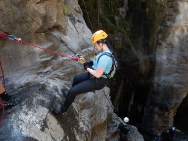 Qatsrin, İsrail, 11 Haziran 2022: Deneyimli bir atlet, İsrail 'in kuzeyindeki Katsrin yakınlarındaki Golan Tepeleri' ndeki Zavitan deresinin kıyısındaki Kara Geçit 'teki bir şelaleye halatla atlamak için ekipmanla birlikte iniyor.
