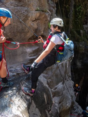 Qatsrin, İsrail, 11 Haziran 2022: Deneyimli bir atlet, İsrail 'in kuzeyindeki Qatsrin yakınlarındaki Golan Tepeleri' ndeki Zavitan deresi Kara Vadi 'deki bir şelaleye halatla atlamak için ekipmanla birlikte iniyor.