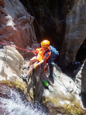 Qatsrin, İsrail, 11 Haziran 2022: Deneyimli bir atlet, İsrail 'in kuzeyindeki Qatsrin yakınlarındaki Golan Tepeleri' ndeki Zavitan deresi Kara Vadi 'deki bir şelaleye halatla atlamak için ekipmanla birlikte iniyor.