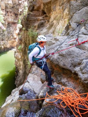 Qatsrin, İsrail, 11 Haziran 2022: Deneyimli bir atlet, İsrail 'in kuzeyindeki Qatsrin yakınlarındaki Golan Tepeleri' ndeki Zavitan deresi Kara Vadi 'deki bir şelaleye halatla atlamak için ekipmanla birlikte iniyor.