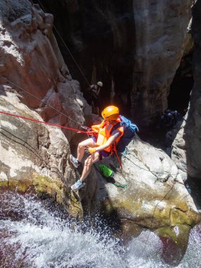 Qatsrin, İsrail, 11 Haziran 2022: Deneyimli bir atlet, İsrail 'in kuzeyindeki Qatsrin yakınlarındaki Golan Tepeleri' ndeki Zavitan deresi Kara Vadi 'deki bir şelaleye halatla atlamak için ekipmanla birlikte iniyor.
