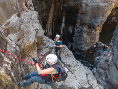 Qatsrin, İsrail, 11 Haziran 2022: Deneyimli bir atlet, İsrail 'in kuzeyindeki Qatsrin yakınlarındaki Golan Tepeleri' ndeki Zavitan deresi Kara Vadi 'deki bir şelaleye halatla atlamak için ekipmanla birlikte iniyor.