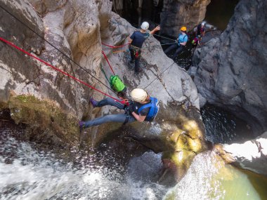 Qatsrin, İsrail, 11 Haziran 2022: Deneyimli bir atlet, İsrail 'in kuzeyindeki Qatsrin yakınlarındaki Golan Tepeleri' ndeki Zavitan deresi Kara Vadi 'deki bir şelaleye halatla atlamak için ekipmanla birlikte iniyor.