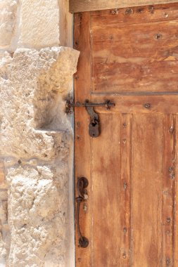 Decorative massive wooden door with a metal bolt and a metal padlock to a residential building in the Arab Christian village Miilya, in the Galilee, in northern Israel