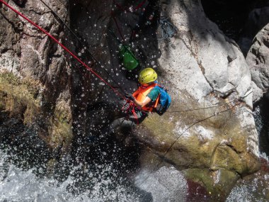 Qatsrin, İsrail, 11 Haziran 2022: Deneyimli bir atlet, İsrail 'in kuzeyindeki Qatsrin yakınlarındaki Golan Tepeleri' ndeki Zavitan deresi Kara Vadi 'deki bir şelaleye halatla atlamak için ekipmanla birlikte iniyor.