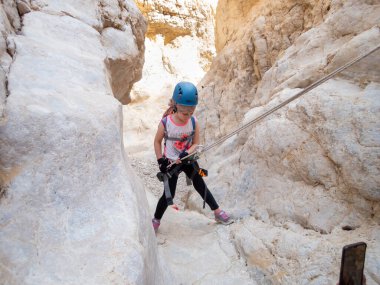 Kudüs, İsrail, Mayıs 05, 2022: Genç atlet İsrail 'in Kudüs kenti yakınlarındaki Rathe deresi yakınlarındaki Judean Çölü dağlarında ipe atlamak için ekipmanla iniyor.