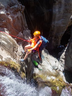 Qatsrin, İsrail, 11 Haziran 2022: Deneyimli bir atlet, İsrail 'in kuzeyindeki Qatsrin yakınlarındaki Golan Tepeleri' ndeki Zavitan deresi Kara Vadi 'deki bir şelaleye halatla atlamak için ekipmanla birlikte iniyor.