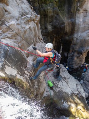 Qatsrin, İsrail, 11 Haziran 2022: Deneyimli bir atlet, İsrail 'in kuzeyindeki Qatsrin yakınlarındaki Golan Tepeleri' ndeki Zavitan deresi Kara Vadi 'deki bir şelaleye halatla atlamak için ekipmanla birlikte iniyor.