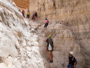 Kudüs, İsrail, Mayıs 05, 2022: Deneyimli bir atlet, İsrail 'in Kudüs yakınlarındaki Rathe deresi yakınlarındaki Judean Çölü' nün dağlarında iple atlamak için ekipman taşıyan genç bir atlete yardım ediyor..