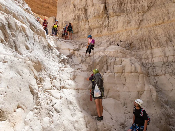 Kudüs, İsrail, Mayıs 05, 2022: Deneyimli bir atlet, İsrail 'in Kudüs yakınlarındaki Rathe deresi yakınlarındaki Judean Çölü' nün dağlarında iple atlamak için ekipman taşıyan genç bir atlete yardım ediyor..