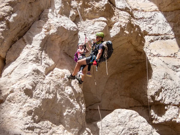 Kudüs, İsrail, Mayıs 05, 2022: Deneyimli bir atlet, İsrail 'in Kudüs yakınlarındaki Rathe deresi yakınlarındaki Judean Çölü' nün dağlarında iple atlamak için ekipman taşıyan genç bir atlete yardım ediyor..
