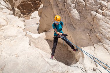Kudüs, İsrail, 16 Nisan 2022: Deneyimli bir atlet, İsrail 'in Kudüs yakınlarındaki Tamarim deresi yakınlarındaki Musevi Çölü' nün dağlarında kırılma ekipmanlarıyla birlikte iniyor.