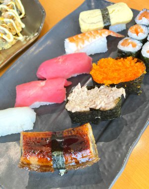 Assorted sushi nigiri and maki big set on slate. A variety of Japanese sushi with tuna, crab, salmon, eel and rolls.