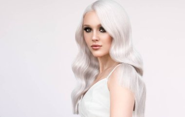 Güzel kadın saçlarını aşırı sarıya boyuyor. Güzellik salonunda yapılan şık bukleler. Moda, kozmetik ve makyaj.