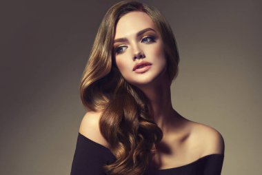Uzun kıvırcık saçlı güzel esmer model kız. Gülümseyen kadın saç stili dalgalı bukleler. Moda, güzellik ve makyaj portresi