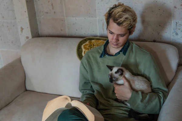 Man Green Sweater Armchair Holding His Siamese Cat While Read — Foto de Stock