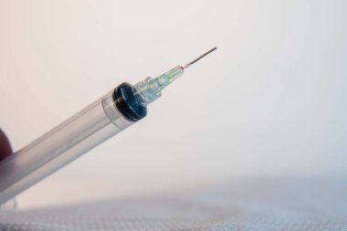 Altında maske olan beyaz bir arka planda ucu biraz kan olan boş bir şırınga. Tıbbi alet. İzole edilmiş bir arka planda şırınga. İğne tıbbi tedavi.