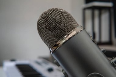Close up of a microphone in a professional music studio. Professional microphone. High quality photo. It is a grey microphone used for professional recording sessions. Copy space for text. 