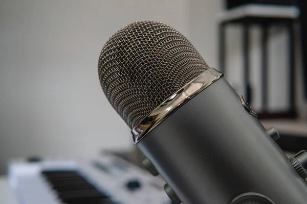 Close up of a microphone in a professional music studio. Professional microphone. High quality photo. It is a grey microphone used for professional recording sessions. Copy space for text.