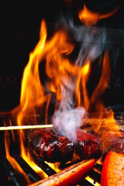 Tam ve ızgarada sosis kes. Siyah resimlerin arka planı. Ateş çok yüksek ve dumanın çıktığını görebilirsiniz..