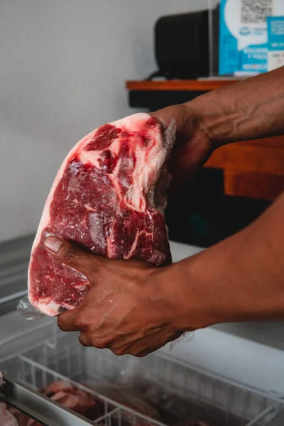 Fine cut of meat in the hands of a butcher taking it out of the freezer. High quality photo. Raw meat. Great fresh cut of meat. Red meat.