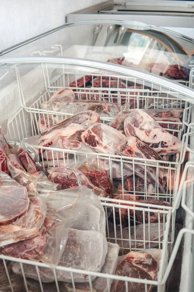 Frozen thin cuts of meat inside a refrigerator. Coolers with lots of frozen meat. Beef and pork cuts.