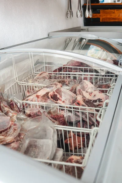 Side view of a series of frozen raw cuts of meat in a refrigerator. Different types of meat cuts. Fine meat. White and clean background.