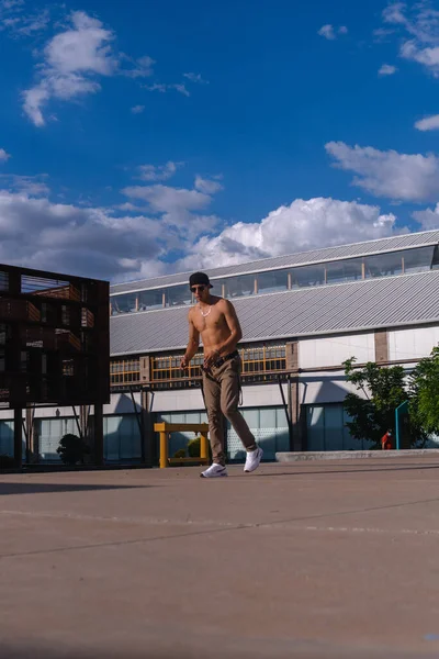 A muscular man outdoors on an esplanade about to parkour. Latin boy dressed in urban clothes rapping in the park. Muscular Latino man training on an esplanade.