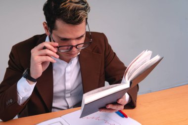 Concentrated elegant man reading at his desk on a white background. Caucasian blond man reading in his office. Business man working in his office. High quality photo