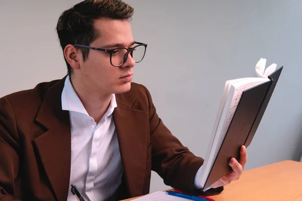 Portrait of a man dressed in a suit reading. Business man on a white background. Blond man reading the notes in his notebook. Blond boy dressed in brown suit, shirt and glasses. High quality photo