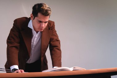 View from below of a man with his hands on his desk thinking about his work. Business man seriously thinking on a white background. Caucasian man in a suit in his office.