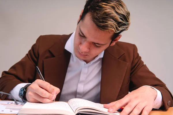 A teacher reviewing papers in the classroom. Business man dressed in cafe suit signing important papers. Man working in his office. A sales executive reading his black pad.