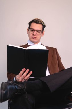 An elegantly dressed intellectual man concentrating on the book he is reading. A businessman on a white background. Man in a suit studying with his black notebook. High quality photo