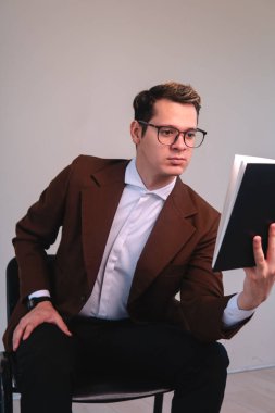 Elegant teacher on white background reading. Concentrated businessman reading. Man with brown jacket, shirt and glasses. A blond Caucasian man reading his notes. High quality photo