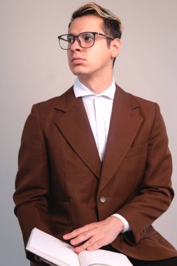 An elegant man looking towards some object. Man with reflection pose. Elegant man posing in front of a white background. Fashionable man with a book in his hand. High quality photo