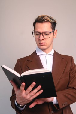 Intellectual man reading a book very attentively on a white background. Teacher with a book in his hand. Man elegantly dressed in a suit, with a shirt and glasses. . High quality photo