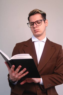 Confused elegant man attentively reading a book. A man in a suit, shirt and glasses studying. Studious man reading the black book of his. Businessman attentively analyzing his book. High quality photo