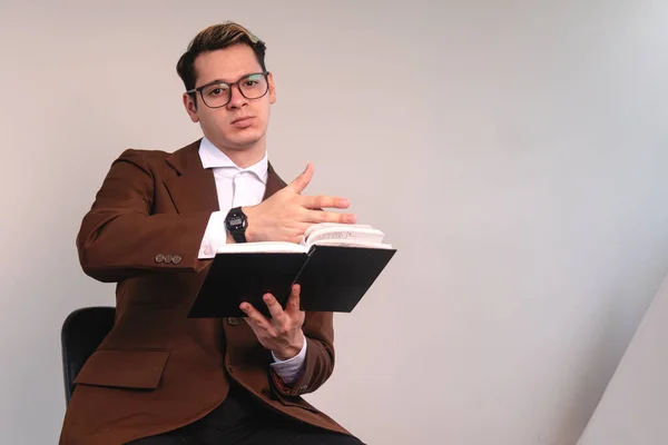 A college professor placing his hand on a book. Elegantly dressed man in jacket, white shirt and glasses, copy space. Business man showing the time on his watch. High quality photo