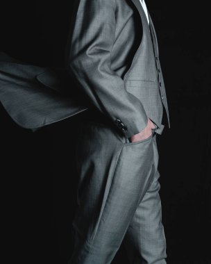Man in a gray suit posing on a black background. Businessman with a jacket and pants walking. High quality photo