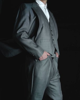an elegant gray suit. a businessman on a black background. Man posing with a jacket and gray pants. High quality photo