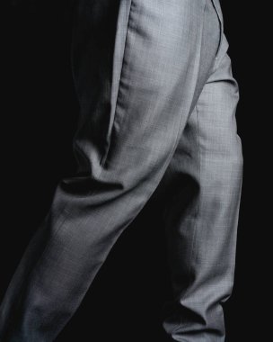 Gray pants on a black background. Fine fabric texture. Elegant suit pants. High quality photo