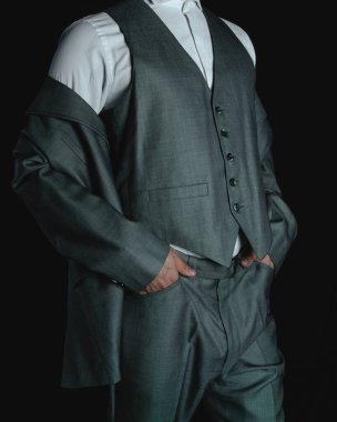 Body of a man in a gray suit. Elegant gray suit. Business man posing on a dark colored background. Man dressed in suit modeling his suit. High quality photo