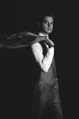 Model in elegant suit posing. Model dressed in a suit and the sack on the shoulder. Model in black and white dressed very elegant. High quality photo