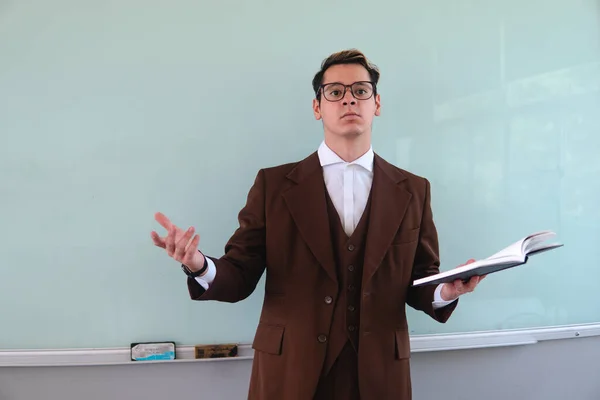 Blond Caucasian man in a suit and glasses giving a class and asking questions to his students. Teacher with questions about his class. Teacher in a classroom giving classes. High quality photo