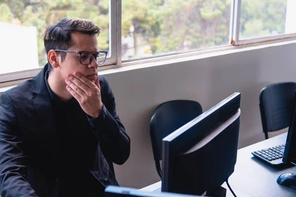 Man with computer with doubt face. Blond Caucasian man who works in an office with a window behind him. Man working with question face. High quality photo